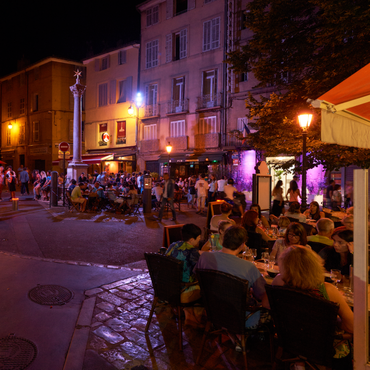 Crowded city street cafe illuminated by modern LED street lights at night