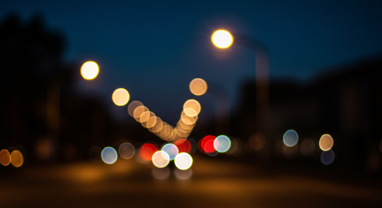 Blurred Street View Due to Astigmatism at Night A nighttime street scene with blurred lights and halos, illustrating the visual distortion caused by astigmatism for affected individuals.