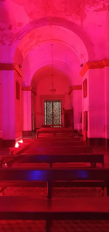 The grandeur of the church interior shines under blue and red lighting, with arches and sacred statues creating a dramatic, reverent atmosphere
