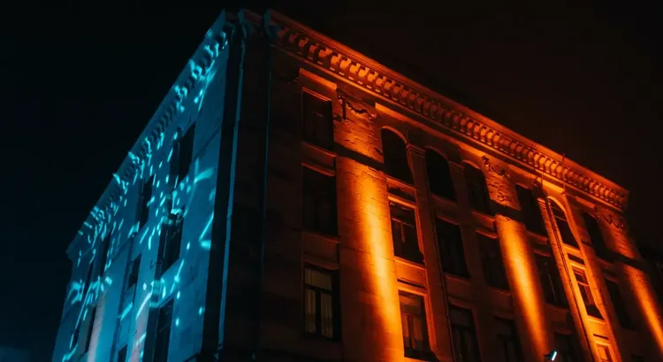 Bright neutral light on a building facade during daytime with scene-based dimming 